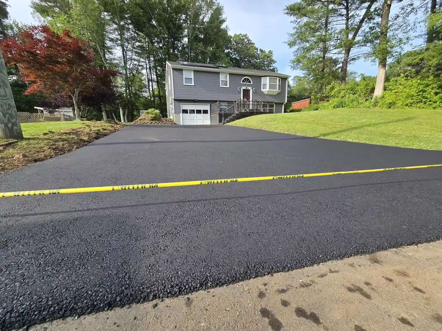 Newly installed asphalt driveway pitched away from the garage